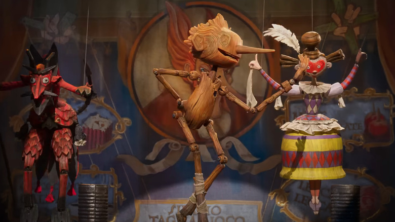 Pinocchio dances on stage with two puppets in del Toro's movie