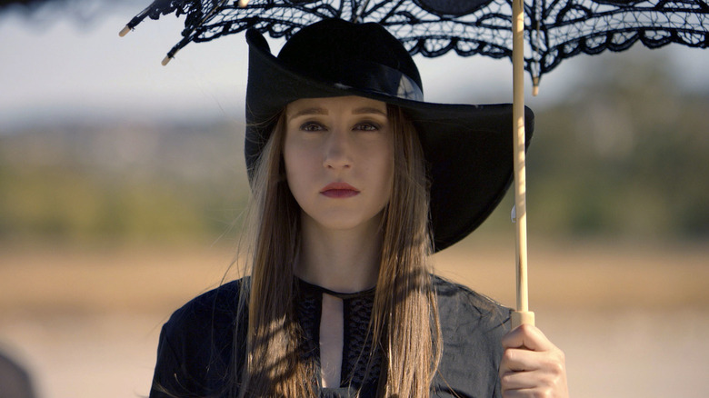 Zoe wears black and holds parasol