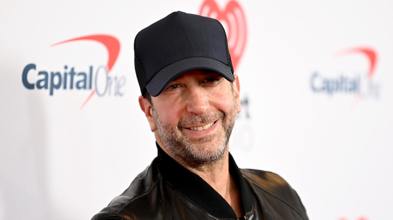 David Schwimmer, in baseball cap and beard, turns to smile