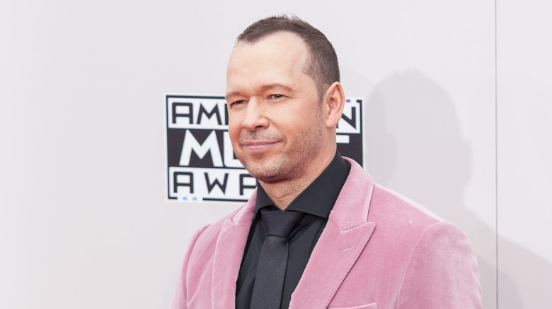 Donnie Wahlberg gives a half -smile while wearing a pink suit jacket