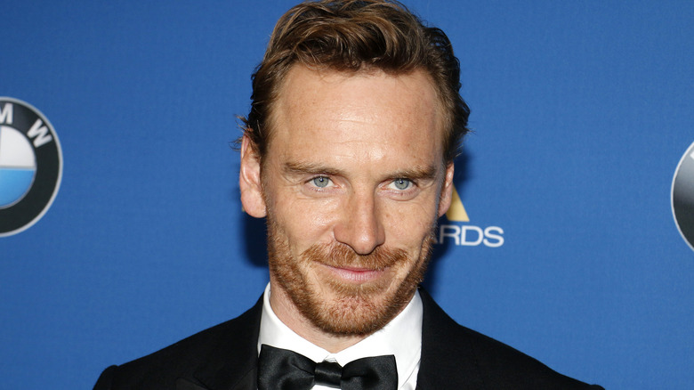 Michael Fassbender smiles while wearing a tuxedo