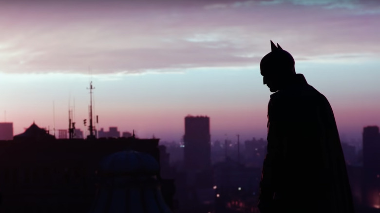 Batman on Gotham rooftop at sunset