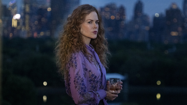 Nicole Kidman stands with drink