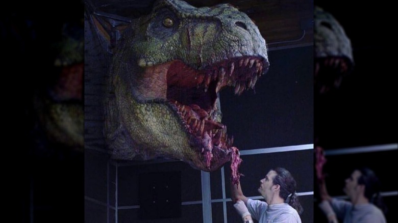 Effects person putting red meat on T-Rex robot