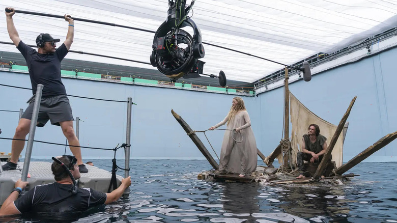 Galadriel and Halbrand on a raft facing camera men in the ocean box studio