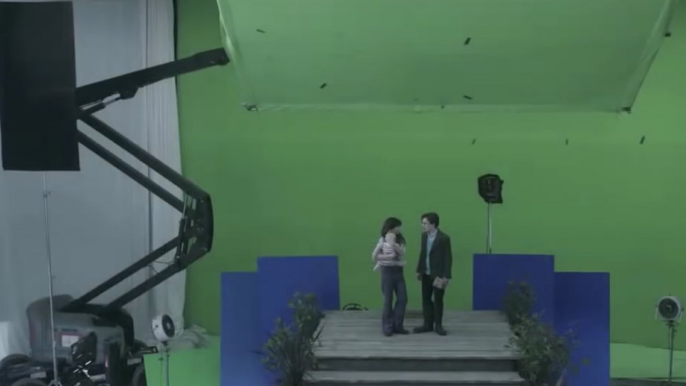 Children stand in front of a green screen house