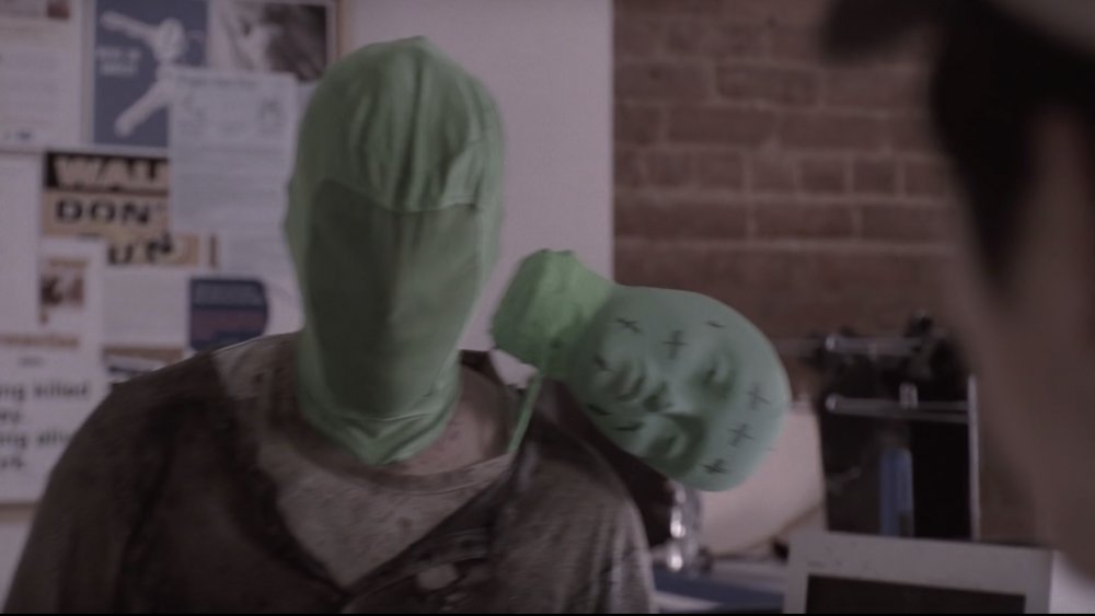 A man in a green mask portrays a zombie