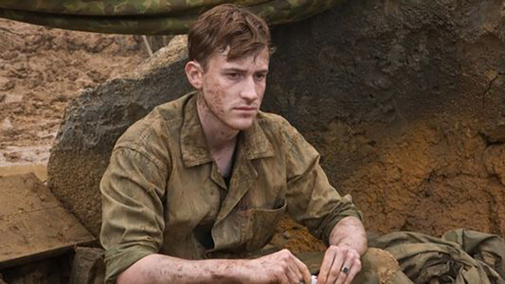 Eugene Sledge sitting on a dirt mound in The Pacific