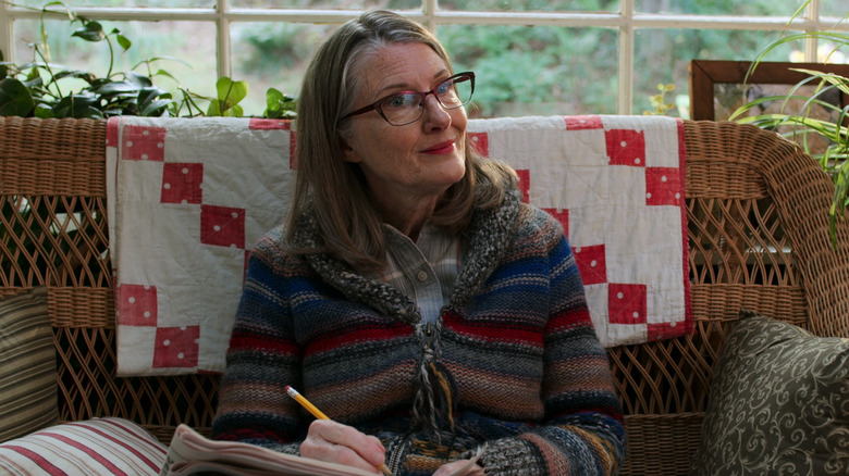 Hope sitting on a wicker couch doing a crossword