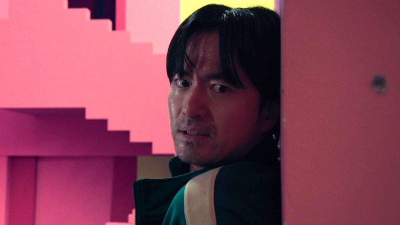 Park Gyeong-seok taking cover behind pink wall in "Squid Game"