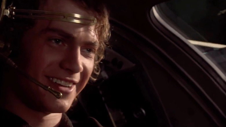 Anakin flying a ship and smiling while wearing a headset