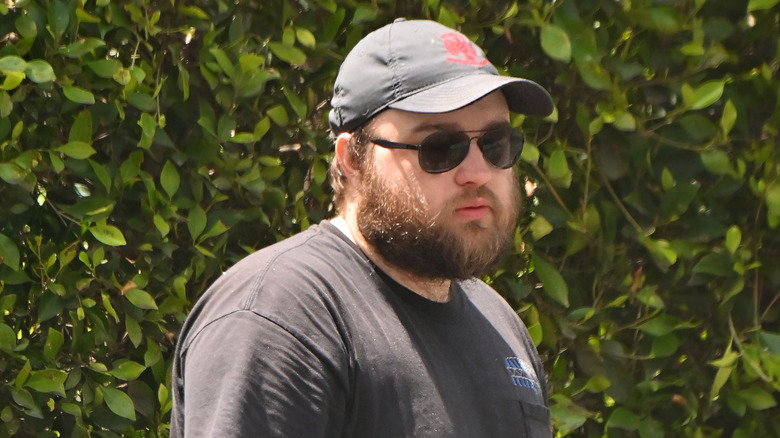 Angus T. Jones wearing sunglasses and a cap outside in 2024