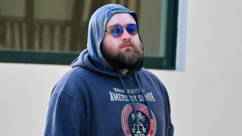 A bearded Angus T. Jones wearing a hoodie and sunglasses as he walks in Los Angeles in 2023