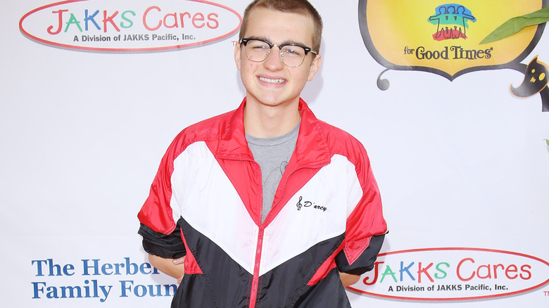 Angus T. Jones wearing glasses and posing for a photo at the Universal Studios Backlot in 2012