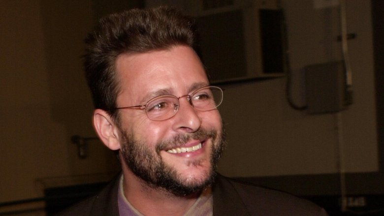 Judd Nelson smiling wearing glasses with beard