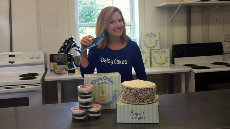 Kim Nelson standing behind Daisy Cake display while holding shark toy