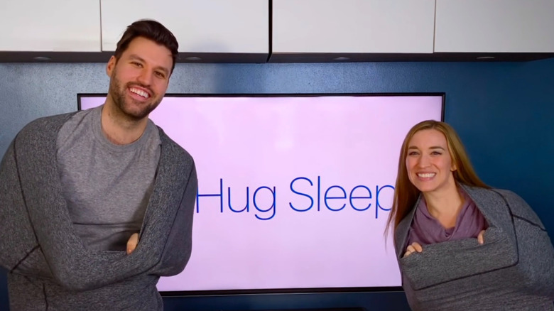 Matt and Angie wearing Hug Sleeps in front of TV screen