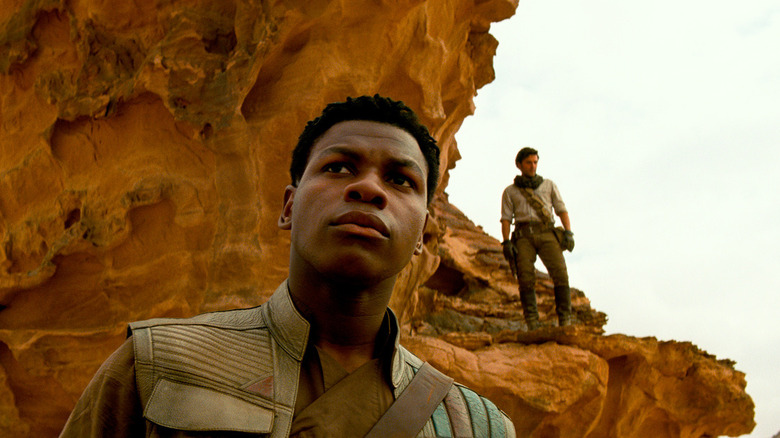 Finn and Poe near a rock