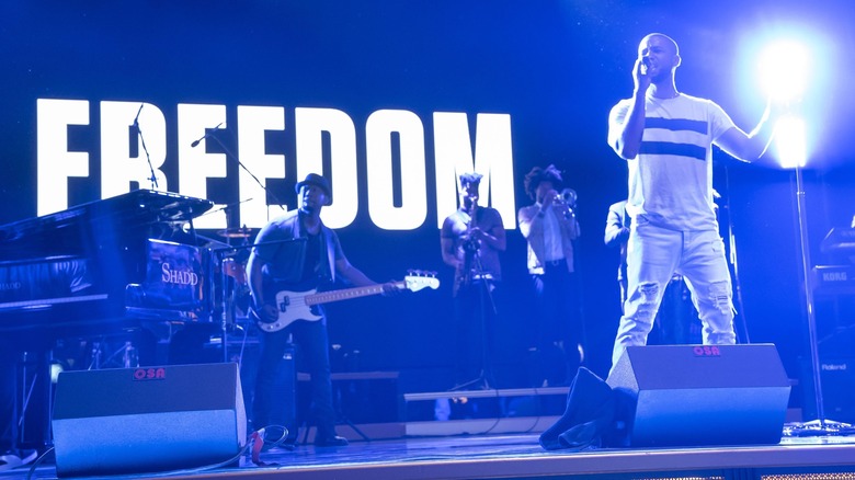 Jamal singing onstage in front of the lit up word freedom