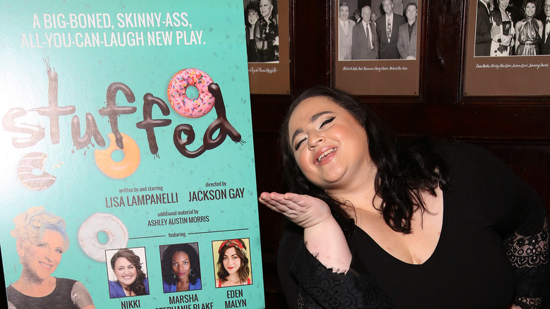 Nikki Blonsky posing in front of a Stuffed poster