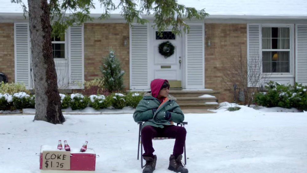 A little boy sits in a chair selling coke