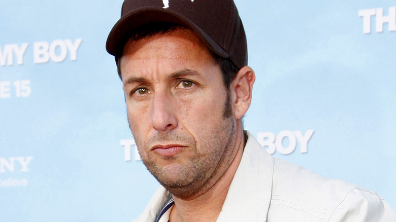 Adam Sandler in close-up wearing a baseball cap at a red carpet event