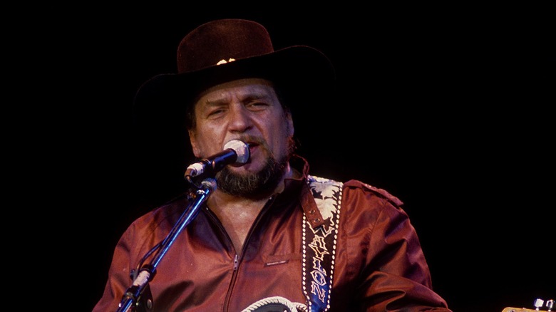 Waylon Jennings plays guitar and sings