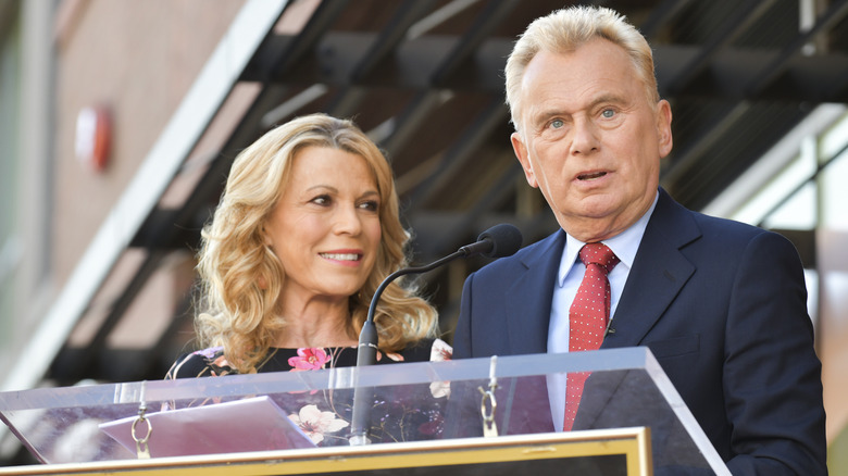 Vanna and Sajak standing behind a podium 