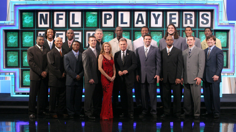 Sajak and Vanna next to NFL players on stage