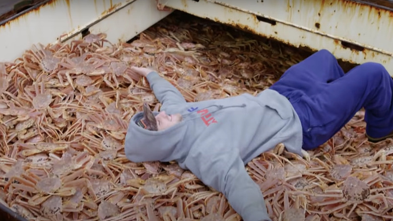 Deckhand lying in huge pile of crabs