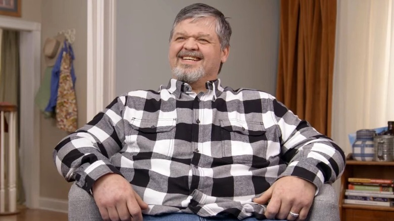 Chris Combs smiling in grey, black, and white flannel