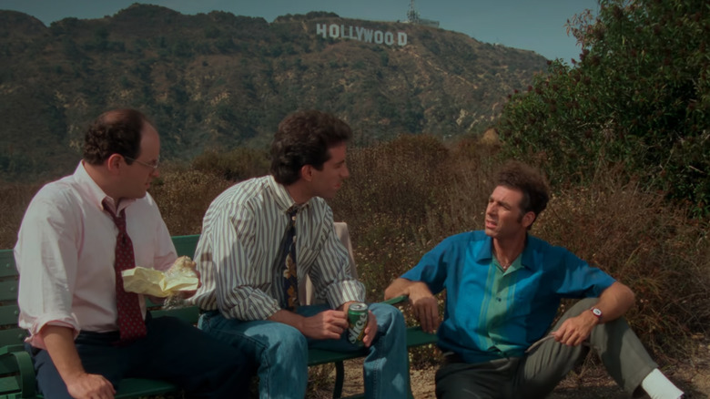 George Jerry and Kramer sitting on park bench with Hollywood sign in background