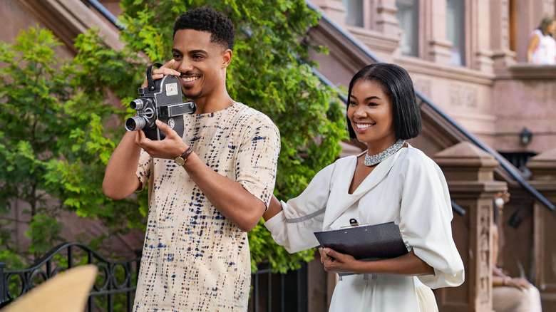 Eric holding camera and Jenna holding clipboard