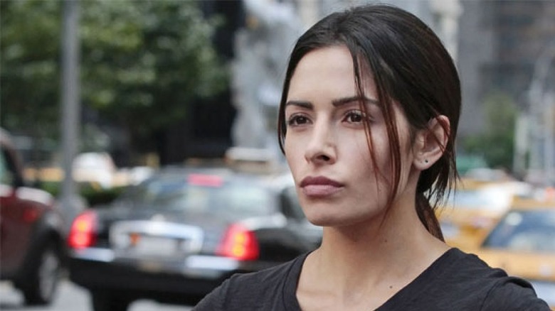 Sameen stands on a sidewalk in front of a busy street