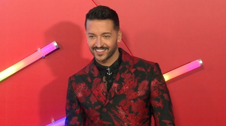 Jai Rodriguez smiling on red carpet in red suit