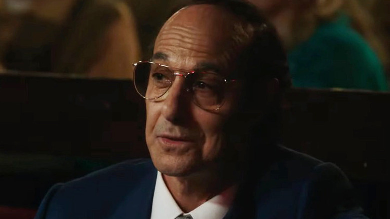 Stanley Tucci wearing glasses and a suit