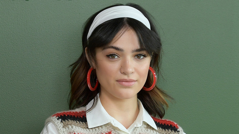 Luna Blaise, wearing a headband, stands against a green background