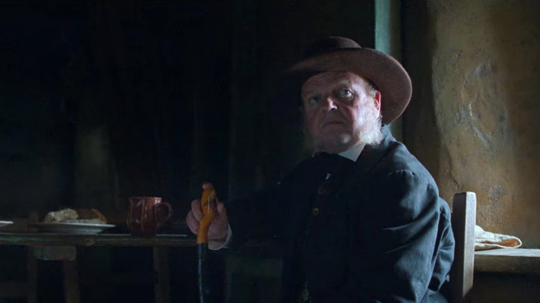 Toby Jones sitting with hat and cane 