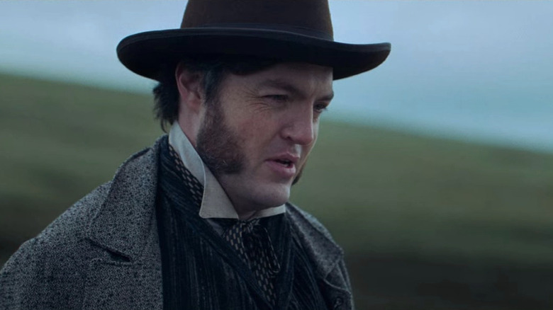 Tom Burke in hat and coat