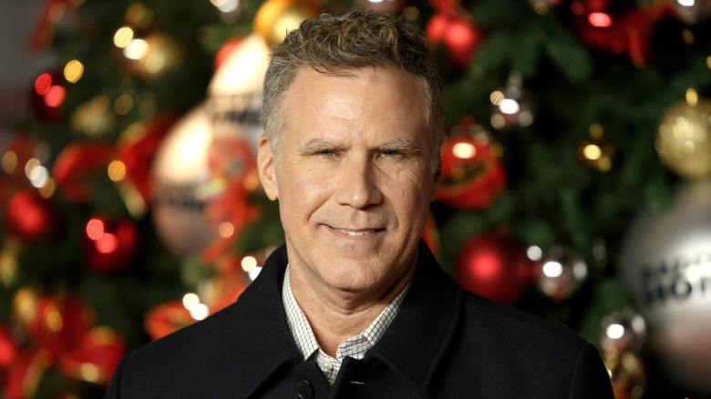 Will Ferrell smiling in front of a Christmas tree