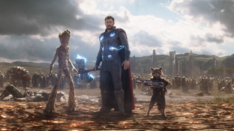 Thor, Groot, and Rocket standing in the middle of battlefield