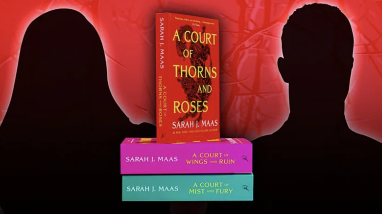 a silhouette of a woman and a man against a bright red backkdrop with the first three ACOTAR paperback novels stacked up in between them