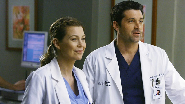 Meredith and Derek in their lab coats smiling on Grey's Anatomy