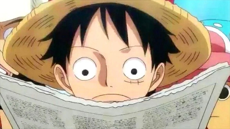 Luffy reading intently with a straw hat on