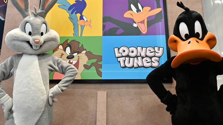 Costumed versions of Bugs Bunny and Daffy Duck pose near framed Looney Tunes art