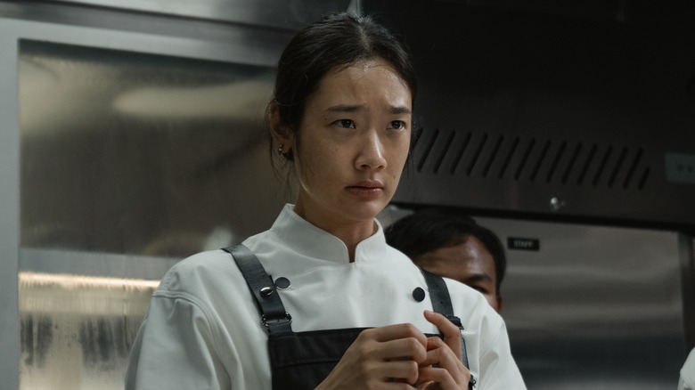 Aoy wearing black apron over white chef's uniform 