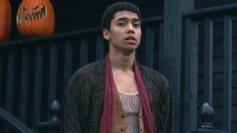 Ambrose Spellman standing next to two pumpkins