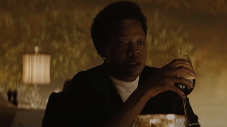 Amanda Waller sits across the table from Bruce Wayne holding a glass of wine