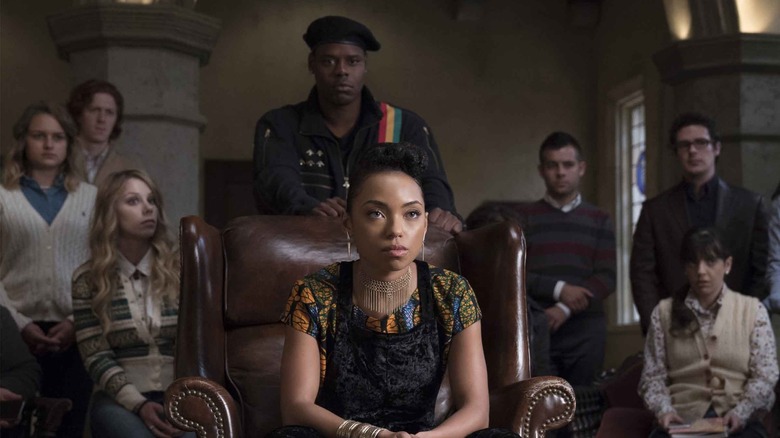 Sam sits on a leather chair, surrounded by her fellow students