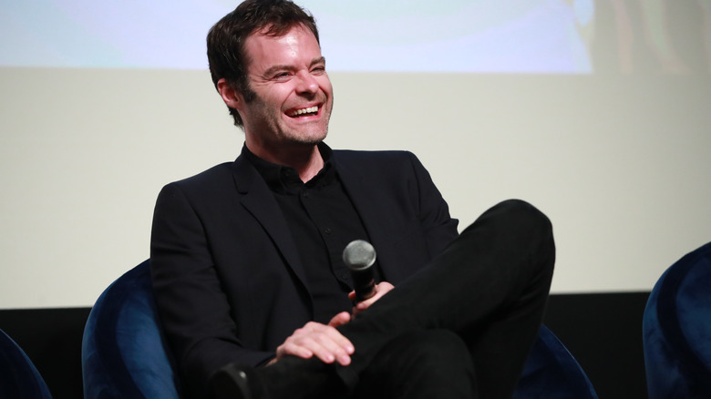 Bill Hader laughing while holding a microphone